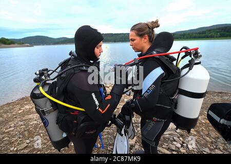 Waldeck, Deutschland. Juli 2020. Die Tauchschüler Constantin Mühr (l.) und Justina Fuchs überprüfen ihre Ausrüstung am Ufer des Edersee vor dem Nachttauchgang. Tief, grün und dunkel - das Tauchen im nordhessischen Stausee ist schon tagsüber ein Abenteuer. Aber wenn Sie den See von einer neuen Seite kennenlernen möchten, können Sie nachts hinein klettern. (Zur Sommerserie 'Night Shift' - 'im Dunkeln in die Tiefe - Nachttauchen am Edersee') Quelle: Uwe Zucchi/dpa/Alamy Live News Stockfoto