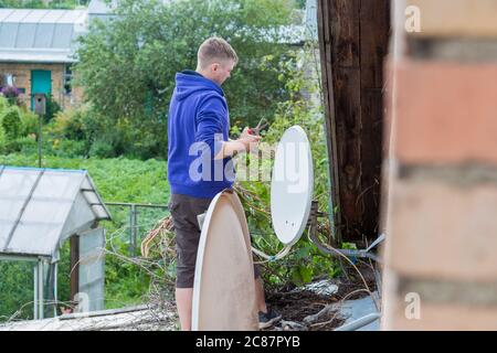 Beschneidung von Pflanzen auf dem Dach eines Dorfhauses. Stockfoto