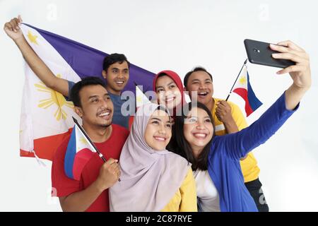 philippinischer Unterstützer, der während des Unabhängigkeitstages ein Selfie-Selbstporträt mit der Flagge der philippinen hält Stockfoto