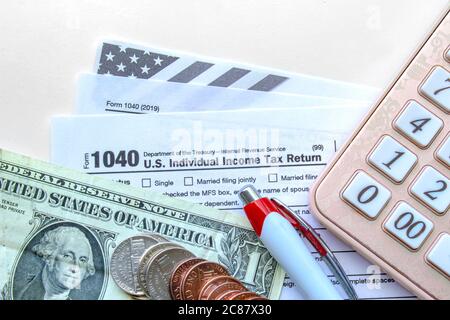 Calgary, Alberta, Kanada. Juli 21, 2020. Vereinigte Staaten von Amerika Steuerformulare mit Münzen, Rechner, ein Stift auf einem weißen Tisch. Steuerzeitkonzept Stockfoto