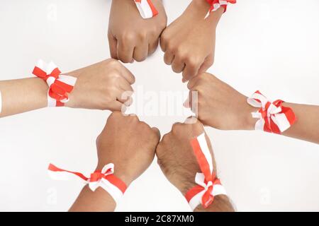 Gruppe von Hand zusammen tragen indonesische rot und weiß Band auf einem Handgelenk. Einheit Konzept Stockfoto