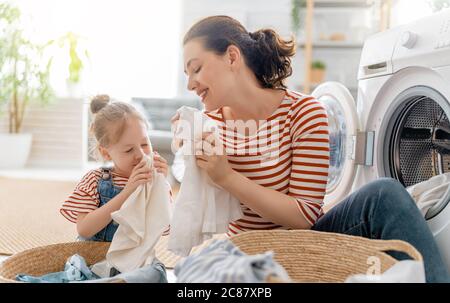 Schöne junge Frau und Kind Mädchen kleinen Helfer haben Spaß und Lächeln, während die Wäsche zu Hause. Stockfoto