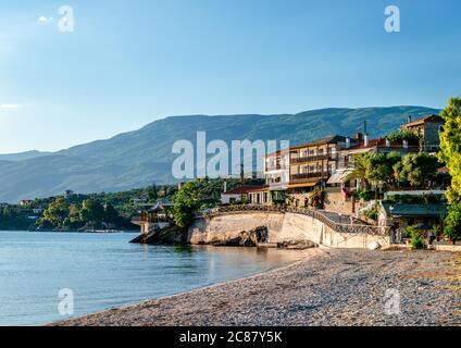 Afissos / Griechenland - Mai 23 2020: Blick auf die Uferpromenade des Dorfes mit Häusern am Meer und dem Berg Pelion im Hintergrund. Stockfoto