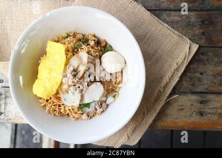 Thailändische Eiernudel mit Fischbällchen und gehacktem Schweinefleisch auf dem Sacktuch des Holztisches Stockfoto