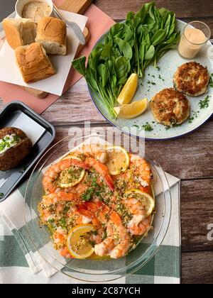 Gegrillter Knoblauch mit Kräuter Garnelen & Krabbenkuchen mit Remoulade-Sauce mit weichem Brötchen und gebackenen Kartoffeln - leckere Mahlzeit Stockfoto