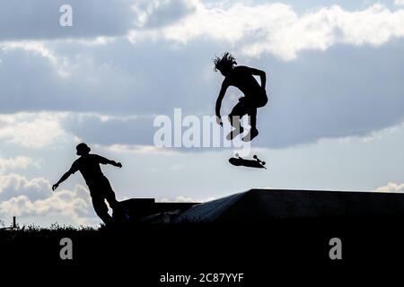 Berlin, Berlin, Deutschland. Juli 2020. Auf einem Skatepark im Tempelhofer Feld am ehemaligen Flughafen Tempelhof sind Silhouetten von Athleten gegen den Abendhimmel zu sehen. Aufgrund der weltweiten Covid-19-Pandemie sind die Sporteinsätze an allen öffentlichen und privaten Sportanlagen, Schwimmbädern und Fitnessstudios in Berlin noch eingeschränkt. Auf Outdoor-Sportanlagen ist die Ausübung kontaktloser Sportarten jedoch erlaubt. Quelle: Jan Scheunert/ZUMA Wire/Alamy Live News Stockfoto