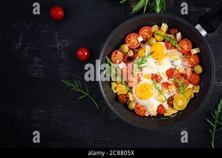 Englisches Frühstück - Spiegeleier, Schinken, Tomaten und Rucola. Amerikanisches Essen. Draufsicht, Overhead, Kopierbereich Stockfoto