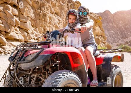 Ein Paar, Kind mit Trainer sind auf roten Quad-Bike in der Wüste Safari fahren Stockfoto