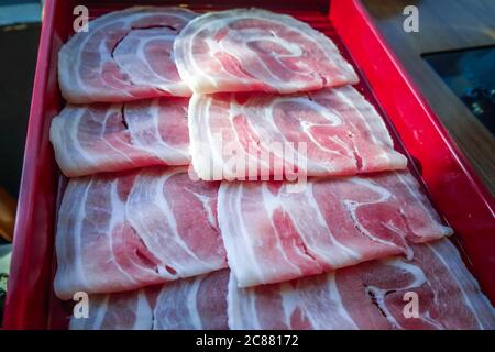 Frische Schweinefleisch-Rinderscheiben in Schale für japanische Sukiyaki oder Shabu-Shabu. Hot Pot Food Restaurant Menü Konzept. Selektiver Fokus. Stockfoto