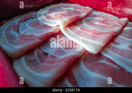 Frische Schweinefleisch-Rinderscheiben in Schale für japanische Sukiyaki oder Shabu-Shabu. Hot Pot Food Restaurant Menü Konzept. Selektiver Fokus. Stockfoto