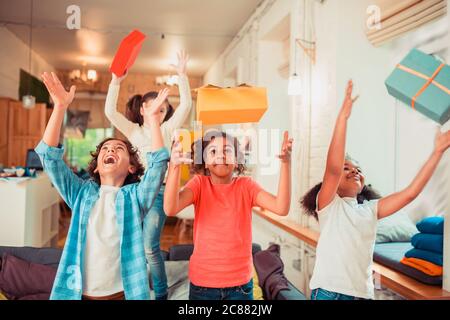 Fröhliche und aktive Kinder werfen Geschenkboxen Stockfoto