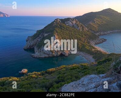 Korfu, Griechenland, Porto Timoni. Blick auf den berühmtesten Doppelstrand und die Bucht von Afionas vom Aussichtspunkt auf dem Weg. Sonnenuntergang goldenes rosa Licht Stockfoto