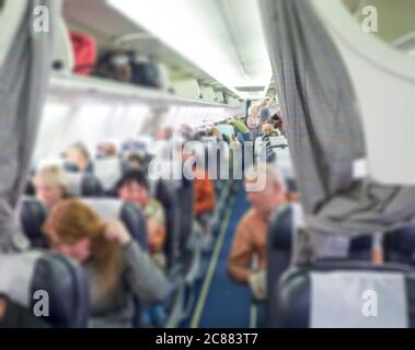 Verschwommener Hintergrund des Innenraums von Verkehrsflugzeugen, selektiver Fokus und abnehmende Perspektive, Passagiere, die auf der Economy-Klasse auf Charter sitzen Stockfoto