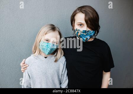 Zwei Kinder tragen Stoffmasken während der Corona COVID-19 Pandemie sind Masken jetzt Pflicht. Stockfoto