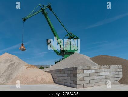 Greifkran füllt Sand von einem Hügel zum anderen Stockfoto