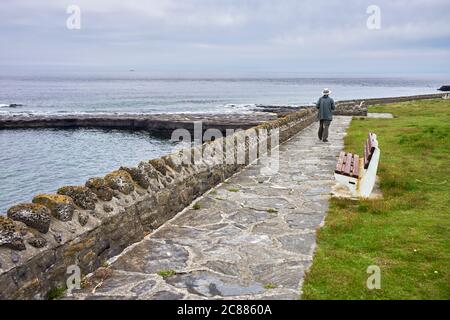 Älterer Mann mit Hut von hinten gesehen beim Spaziergang am Meer in Port St Mary, Isle of man Stockfoto