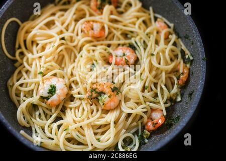 Spaghetti mit Garnelen Petersilie und Knoblauch in einer Pfanne für ein mediterranes Fischgericht, ausgewählter Fokus, enge Schärfentiefe Stockfoto