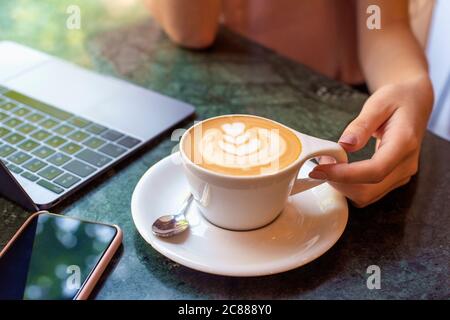 Eine Aufnahme aus einem hohen Winkel, in der eine Frau am Cafe-Schreibtisch saß und ihren Cappuccino trank. Stockfoto