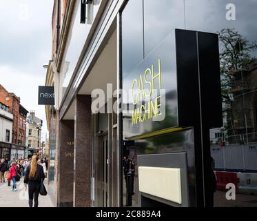 Außenansicht eines bekannten britischen Einzelhandelsunternehmens, das einen Geldautomaten in der Nähe des Eingangs zeigt. Gesehen an einem geschäftigen Wochenende in Cambridge City. Stockfoto