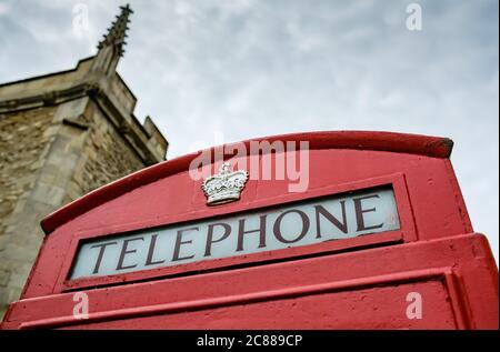 Nahaufnahme des Dachs einer altmodischen britischen roten Telefonbox, mit Schriftzug und goldlackierter Krone in der Nähe des Dachbereichs. Stockfoto