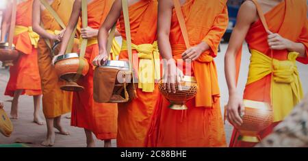 In der Nähe von buddhistischen Novizen Mönche, die ihre Almosenschüsseln tragen, um am frühen Morgen Almosenschüsseln zu machen. Luang Prabang, Laos. UNESCO-Weltkulturerbe Stadt. Stockfoto