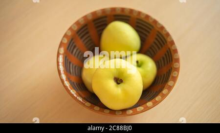Ripe green apples in a clay bowl on the wooden table Stockfoto