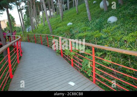 Rote Brücke außerhalb des Nationalparks. Green Leaf Park. Es gibt weiße runde Lichter auf dem Boden. Brückenstraße im Park . Stockfoto