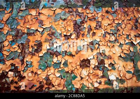 Textur einer Metallwand mit Rissen und Kratzern, die als Hintergrund verwendet werden kann. Gelbe und grüne Peeling-Farbe auf einer Metalloberfläche. Muster. Stockfoto
