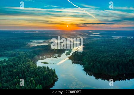 Sonnenaufgang oder Morgengrauen über dem Fluss. Sonnenuntergang über Wald oder See. Sonnenaufgang über der schönen Natur in gemäßigter Zone. Luftaufnahme. Stockfoto