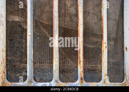 Textur einer Metallwand mit Rissen und Kratzern, die als Hintergrund verwendet werden kann. Die Struktur des Metallgitters aus einer alten Batterie. Muster. Stockfoto