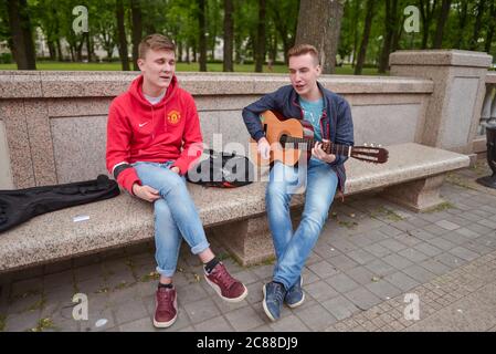 Minsk / Weißrussland - 5. Juni 2019: Zwei junge belarussen singen und spielen Gitarre im Stadtpark Stockfoto