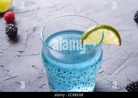 Leckeres blaues Cocktailgetränk mit Basilikum Chia Samen, Zitruslime Scheibe, Himbeere und Brombeere Beeren im Glas, gesundes Sommergetränk Stockfoto