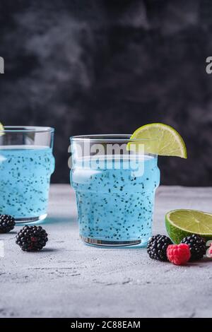 Leckeres, blaues Cocktailgetränk mit Basilikum Chia Samen, Zitruslime Scheibe, Himbeere und Brombeere Beeren in zwei Glas, gesundes Sommergetränk Stockfoto