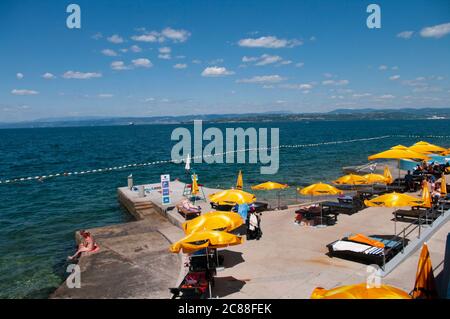 IZOLA, SLOWENIEN - 16. JULI 2020: Küste mit gelben Sonnenschirmen am Strand von Izola über der Adria, Slowenien. Stockfoto