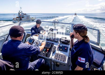 Kommandant LT Rebecca Anderson Royal Navy (rechts) im Ausland HMS Biter mit CPO (ETME) Graeme Hinton am Steuer und ab (SEA) Ryan Dargue während Ship's in Company Close-in Manöver entlang der nördlichen Antrim Küste. Die Coronavirus-Pandemie hat logistische Herausforderungen an Bord eines Kriegsschiffs ausgelöst, das die Kommandanten der Zukunft ausbildet. Stockfoto