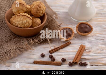 Schokoladenstückchen und Glas Milch im Hintergrund. Nüsse backen mit Schokolade und Zimt Stockfoto