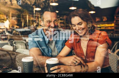 Ein Paar sitzt in einem Café und lächelt. Ein Paar auf einem Date in einem lokalen Café. Stockfoto