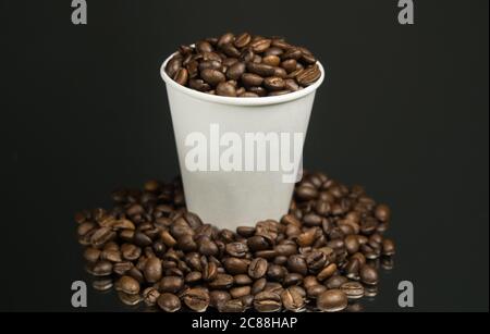 Papiertasse mit Kaffee und Kaffeebohnen auf dem Tisch Stockfoto