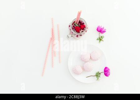 Beeren-Smoothie mit Strohhalmen, Marshmallow und Anemonen Blumen auf weißem Hintergrund. Flach liegend. Stockfoto