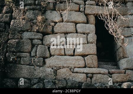 Kleines rechteckiges Loch in einer alten Steinmauer Stockfoto