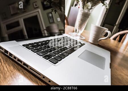 Detailansicht eines bekannten Computerherstellers, geöffnet auf einem Schreibtisch für Heimarbeiter, während der Mitarbeiter nicht am Schreibtisch ist. Stockfoto