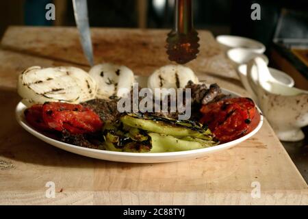 Gebratenes Fleisch mit gegrilltem Gemüse auf einem Teller, auf einem Holzbrett Stockfoto