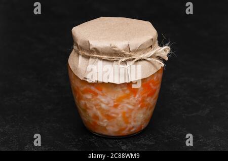 Hausgemachtes Sauerkraut mit Karotte in einem Glas auf schwarzem Hintergrund. Fermentierte Lebensmittel. Natürliches Probiotikum. Gesunde Ernährung und Diät-Konzept. Nahaufnahme Stockfoto