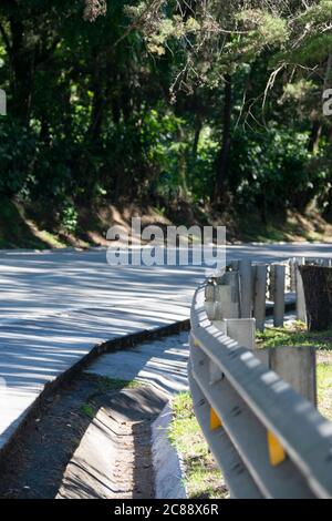 Straßenverlauf von Guatemala, Straße nach La Antigua Guatemala, ländliche Asphaltstraße, gebogene Schutzschiene, Sicherheits-und Sicherheitsmaßnahmen. Stockfoto