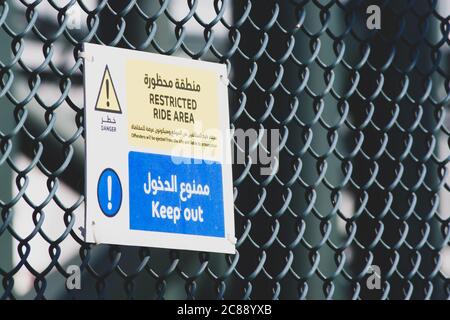 'Dubai, Dubai/Vereinigte Arabische Emirate - 03/07.2020: Mit Einschränkungen ist das Warnungszeichen auf Zaun in Arabisch und Englisch mit Kopierplatz' Stockfoto