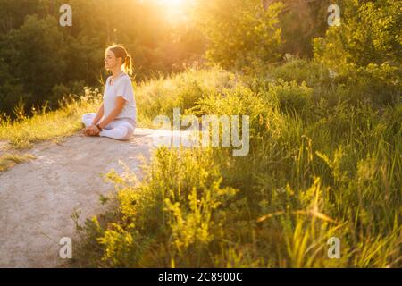 Voller Frieden und Ruhe junge Frau meditiert in Lotusposition mit geschlossenen Augen sitzen Stockfoto