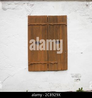 Geschnitzte hölzerne Fensterläden mit Herzen auf einer weißen Ziegelwand. Stockfoto