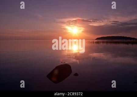 Wunderschöne bunte rosa und lila Sonnenuntergang und Reflexionen mit Blick auf die Inseln in den Gewässern der Ostseeküste machen ein schönes Hintergrundbild Stockfoto