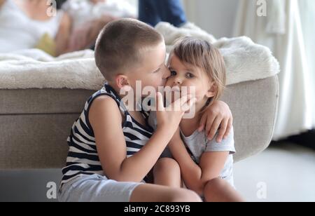 Junges Kind küsst die Wange seiner Schwester unter den Lichtern mit Ein verschwommener Hintergrund Stockfoto