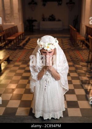 Vertikales Porträt einer Frau, die in einer Kirche mit Rosenkranz kniet und betet Stockfoto